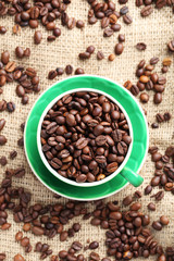 Brown roasted coffee beans in cup on sackcloth