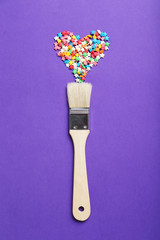 Colorful sprinkles with paintbrush on the purple background