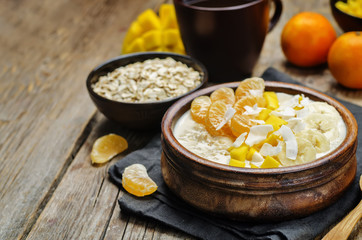 Oatmeal with mango, banana, tangerine oranges and coconut flakes