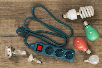 various lamps and multi-outlet  extension cord on a wooden table