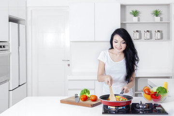 Obraz na płótnie Canvas Pretty Asian woman cooking on stove
