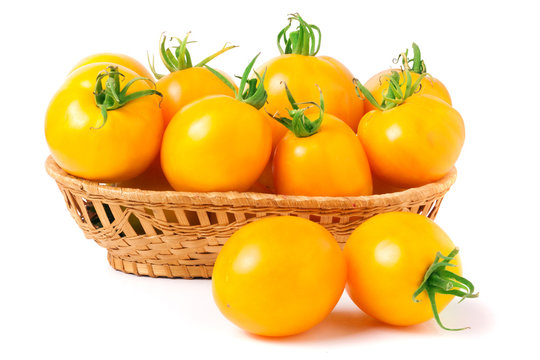 yellow tomatoes in a wicker basket isolated on white background