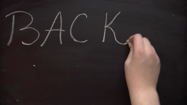 Writing on the blackboard, back to school. The girl writes on a blackboard with chalk.