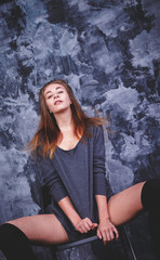 Naklejka premium young sexy girl in a stylish jacket is sitting on chair