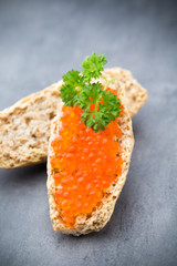 Bread with fresh cream cheese and red caviar on table.