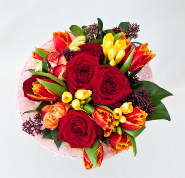 Closeup of a bouquet of Roses, Tulips, Freesia, Skimmia on gray background