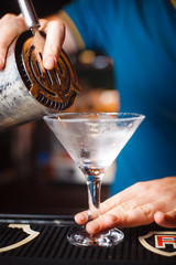 The bartender pours a drink on a cold glass closeup