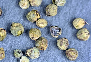 Many green peppercorns on slate