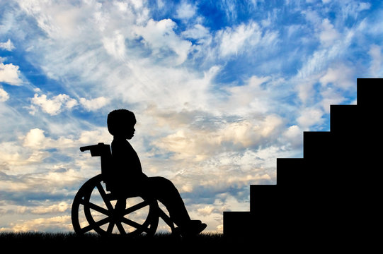 Disabled child sitting in wheelchair front of stairs