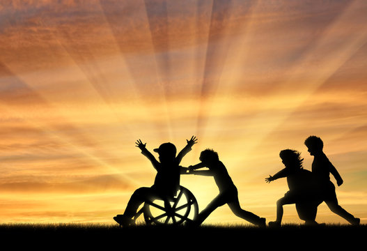 Happy boy in wheelchair playing with children sunset