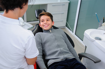 Photo of little boy having mouth checkup in dental clinic