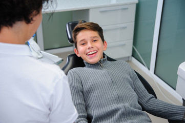 Photo of little boy having mouth checkup in dental clinic