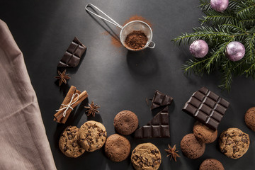 Chocolate christmas cookies and gingerbreads on a black background with chocolate pieces, orange...