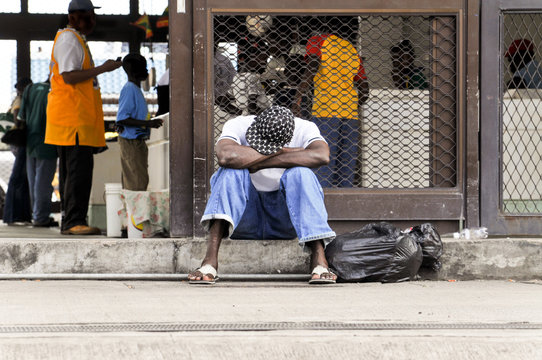 Hungriger Obdachloser sitzt auf dem Bürgersteig vor einem Imbiss