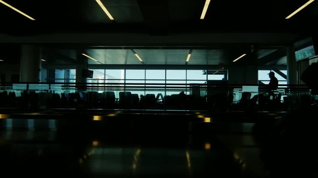 A crowd of people moved by a large JFK airport terminal in New York. Silhouettes without recognizable faces