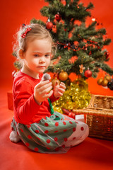 pretty little girl decorates the Christmas tree with beautiful balls