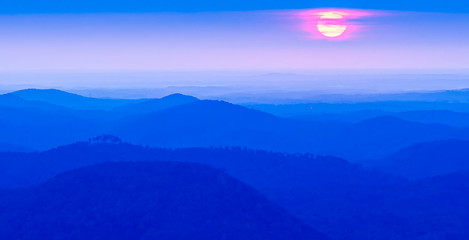 sunrise sun peeks through the clouds over mountain range