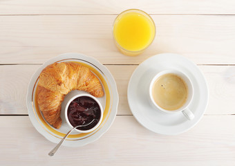 croissant, jam, coffee and orange juice on wooden background