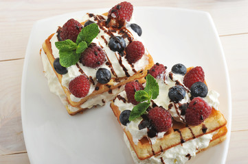 Belgian waffles with raspberries and blueberries on wooden backg