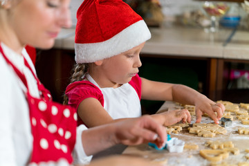 Mother and daughter are preparing gingerbread for Christmas