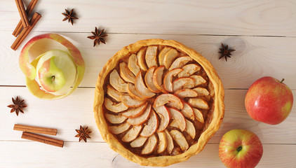 Apple tart with cinnamon and apples on a white wooden background