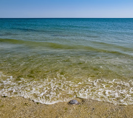 On a hot cloudless day the waves rolled ashore sandy beach