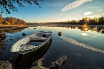 Calm lake with rowboat in autumn scenery - Powered by Adobe