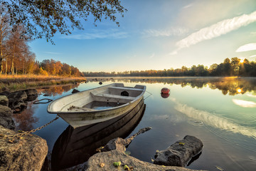 Idyllic autumn lake scenery with white rowboat