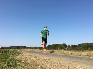 Runner on country road on beautiful blue sky day