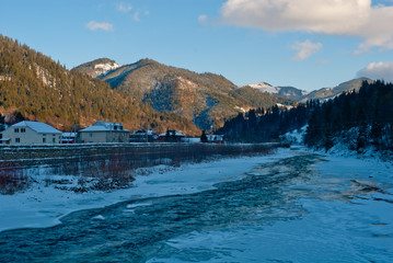 sunny winter mountain landscape with river near village houses