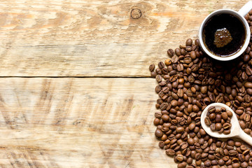cup of coffee, beans and spoon on wooden background