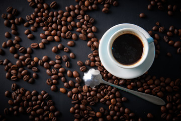 Cup of coffee and coffee beans on a black background. View from above. Shooting in studio.
