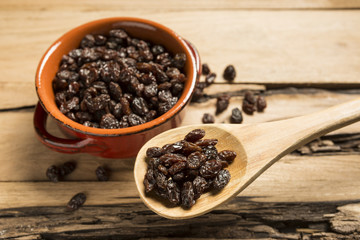 Closeup of Raisins in a wooden spoon on wood table
