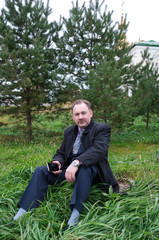 Man holding a cell phone while sitting on the grass 