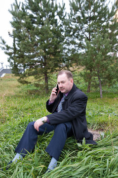 Man talking on the phone while sitting near the firs  
