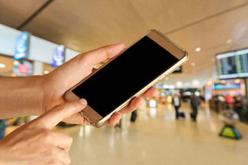 woman hand hold and touch screen smart phone, tablet,cell phone over airport terminal blur background with bokeh light