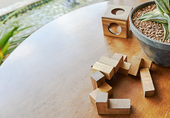 Toys, wooden block, are put on wooden table, in the bottom right corner of picture and decorated with little tree in flower pot.