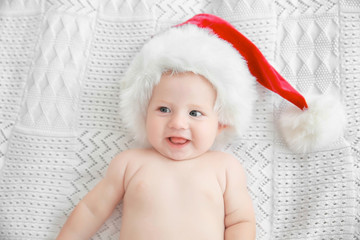 Little baby in Christmas hat on white bed