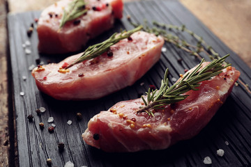 Raw steak with herb and spices on wooden cutting board