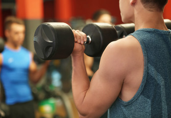 Fototapeta na wymiar Athletic man training with dumbbells in gym