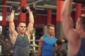 Naklejka premium Athletic man training with dumbbells in gym