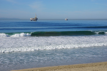 Fototapeta na wymiar oil platforms and surfers in pacific ocean