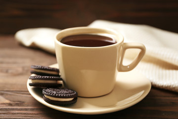 Saucer with cup of coffee and tasty chocolate cookies on wooden table