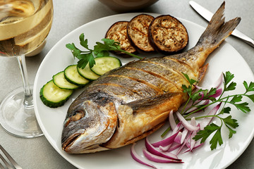 Tasty fish with vegetables on kitchen table