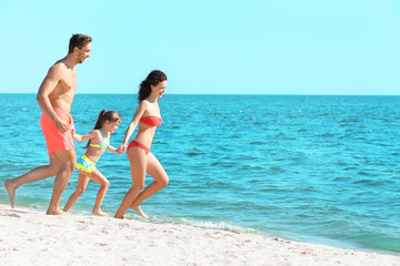 Cheerful parents and little girl going to swim