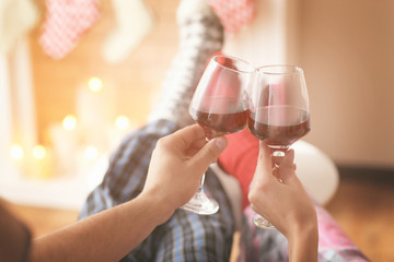 Couple drinking wine in front of fireplace at home
