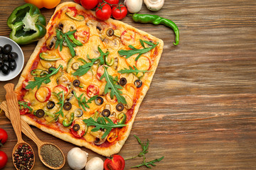 Delicious pizza with ingredients on wooden background