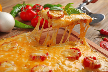 Delicious pizza with melted cheese on wooden cutting board, closeup