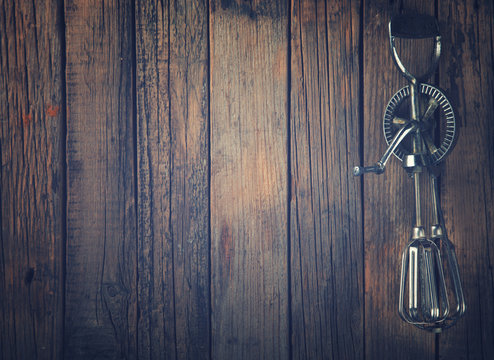 Whisk Beating Eggs On Wooden Background.Hand Mixer.Vintage Style.Top View. Copy Space.Space For Text.Toned Image.