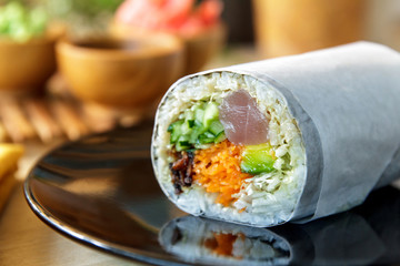 sushi burrito roll on shiny black plate © Odua Images